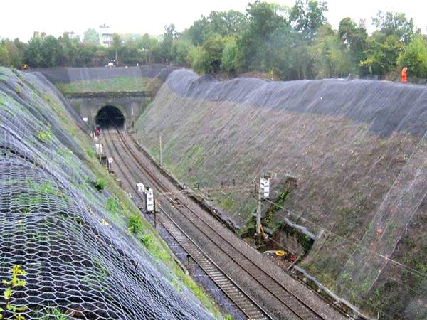 Hexagonal netting system is placed on the slope along the railway.
