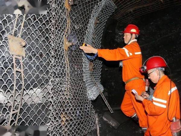 Dos trabajadores están parados en la máquina y conectan la malla Mincon.