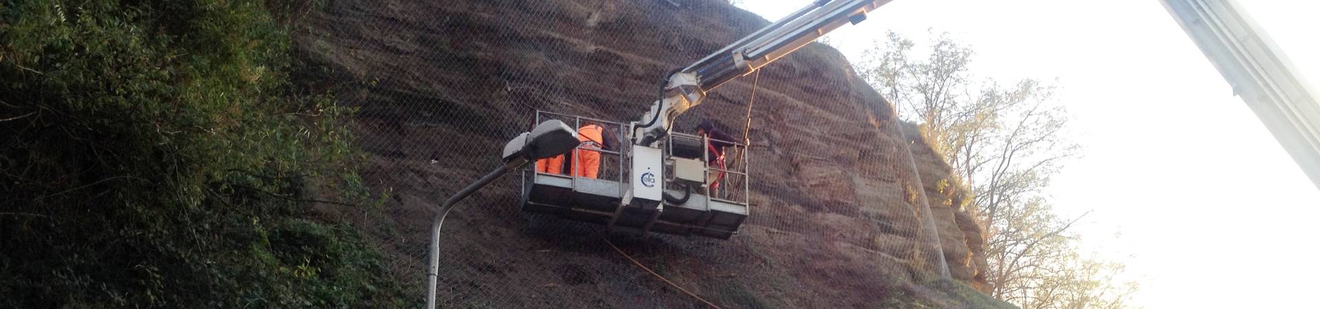 A crane is lifting a roll of Rockcon® mesh for installation.